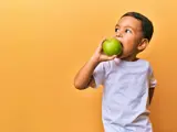 A banner with a yellow background, featuring a young boy in a white shirt, eating a green apple loading=